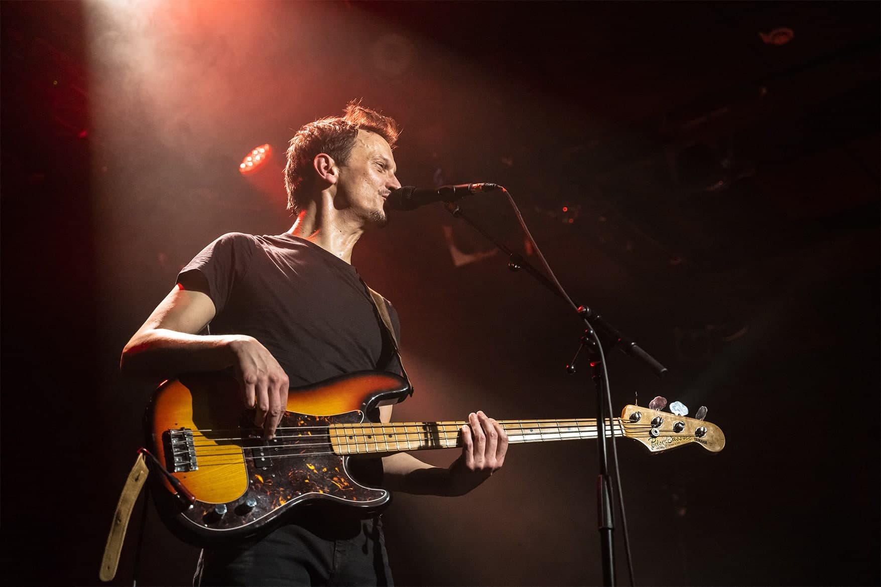 Guillaume Farley en concert, basse en main, sous un éclairage de scène rouge